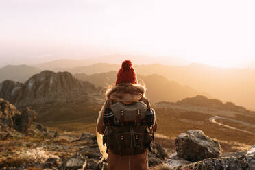 Rückenansicht eines unerkennbaren Wanderers, der auf einem Stein steht und die herrliche Landschaft des Hochtals an einem sonnigen Tag betrachtet - ADSF23164