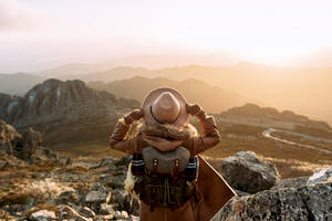 Rückenansicht eines unerkennbaren Wanderers, der auf einem Stein steht und die herrliche Landschaft des Hochtals an einem sonnigen Tag betrachtet - ADSF23165
