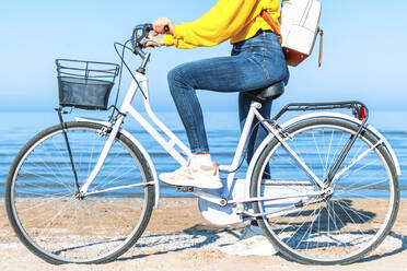 Frau mit Fahrrad am Meer stehend an einem sonnigen Tag - DAF00040
