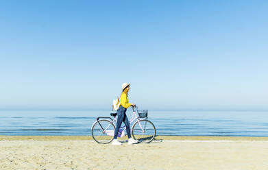 Frau zu Fuß mit Fahrrad am Strand - DAF00043