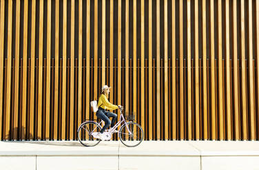 Junge Frau mit Rucksack, die auf dem Fußweg Fahrrad fährt - DAF00044