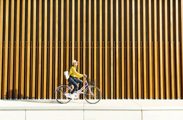 Young woman with backpack cycling bicycle on footpath - DAF00044