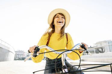 Glückliche Frau mit Hut und Fahrrad an einem sonnigen Tag - DAF00048