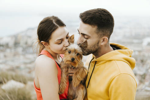 Girlfriend and boyfriend kissing pet together - MIMFF00712