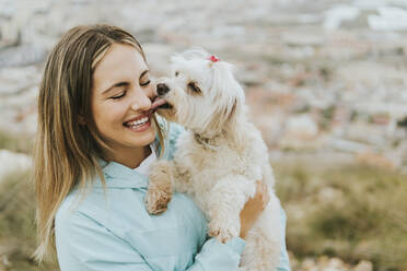 Fröhliche Frau lächelt und hält einen Malteserhund - MIMFF00717