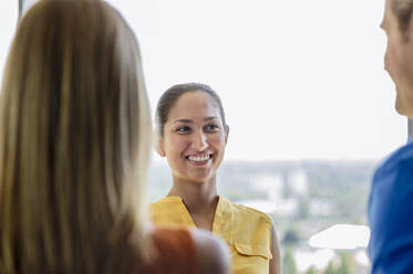 Geschäftsfrau lächelnd mit Blick auf einen Kollegen im Büro - BMOF00544