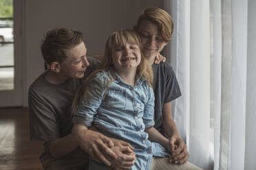 Zwei Brüder und eine Schwester sitzen zusammen in einem Studio mit natürlichem Licht - CAVF93988