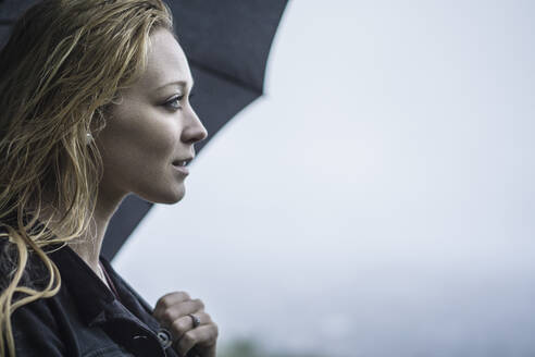 Blonde female fashion model discovering city in the rain - CAVF94000