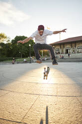 Skateboard enthusiast doing 360 flip while skateboarding in park - CAVF94007