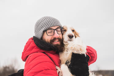 Ein glücklicher Mann umarmt seinen Spaniel bei einem Spaziergang. - CAVF94010