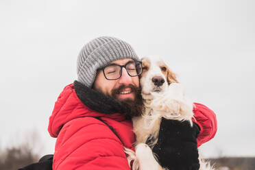 Happy male person hugs his spaniel dog at a walk. - CAVF94010