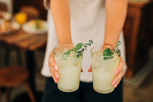 Woman holding non-alcoholic beverage, cold lemonade with mint and ice - CAVF94017