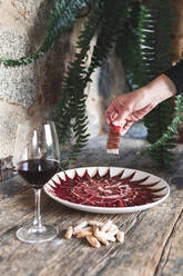 Junge Köchin arrangiert rotes Fleisch in einem Teller mit Getränken auf einem Tisch im Restaurant - JAQF00543