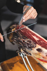 Chef cutting ham with kitchen knife at restaurant - JAQF00546