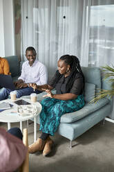 Young businesswoman gesturing while discussing with colleagues in office - ZEDF04052