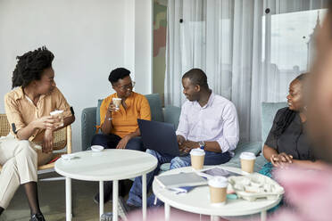 Male and female entrepreneurs discussing while having coffee at coworking office - ZEDF04053