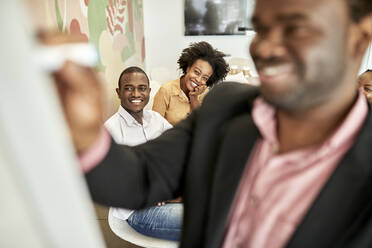 Lächelnde männliche Fachkraft, die mit Kollegen im Büro eine Geschäftsstrategie am weißen Brett diskutiert - ZEDF04073