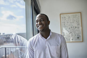 Smiling male professional looking through window at office - ZEDF04131