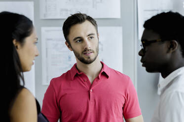 Male professional looking away while standing amidst colleagues in office - BMOF00557