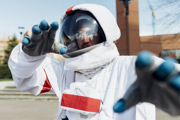 Junger männlicher Astronaut im Raumanzug gestikuliert im Freien - MEUF02383