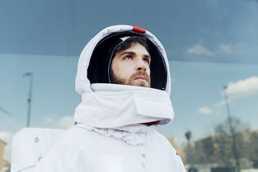 Thoughtful male astronaut in space suit looking away in city - MEUF02390