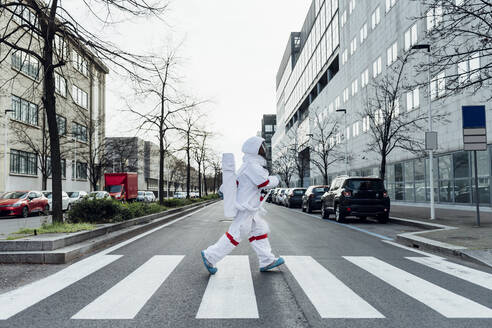 Astronautin beim Überqueren der Straße in der Stadt - MEUF02392