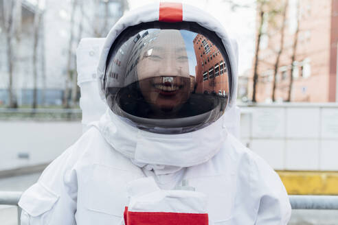 Lächelnde Astronautin im Raumanzug in der Stadt - MEUF02398