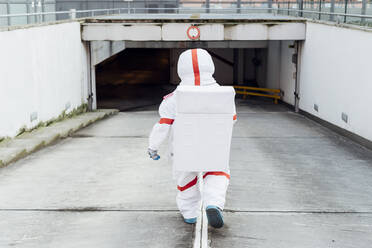 Weibliche Astronautin im Raumanzug auf dem Weg nach unten in der Tiefgarage - MEUF02402