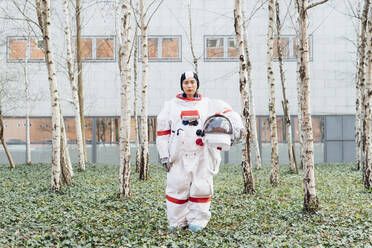 Astronautin mit Weltraumhelm im Garten stehend - MEUF02406