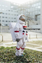 Junge Astronautin im Raumanzug steht auf Gras an einem sonnigen Tag - MEUF02409