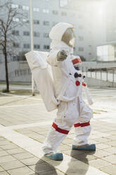 Weibliche Astronautin, die auf dem Fußweg vor dem Gebäude steht und zeigt - MEUF02416