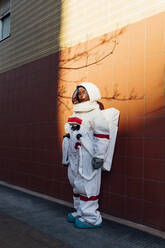 Weibliche Astronautin im Raumanzug steht bei Sonnenuntergang an der Wand - MEUF02458