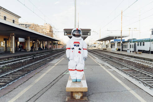 Junge Astronautin steht auf einer Bank im Bahnhof - MEUF02468