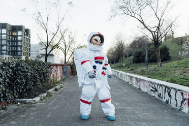 Weibliche Astronautin mit Alien-Maske steht auf einem Fußweg - MEUF02484