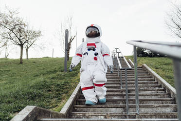 Weibliche Astronautin, die sich auf einer Treppe im Park nach unten bewegt - MEUF02486