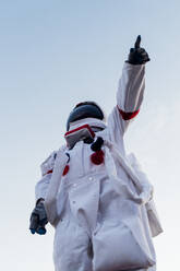 Young female astronaut pointing while wearing space suit - MEUF02490