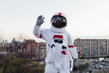 Female astronaut waving during sunset - MEUF02491