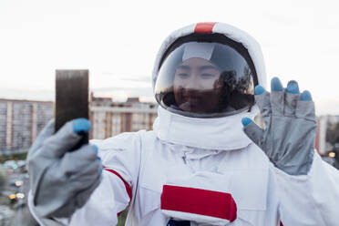 Junge Astronautin winkt bei einem Videogespräch über ein Smartphone - MEUF02496