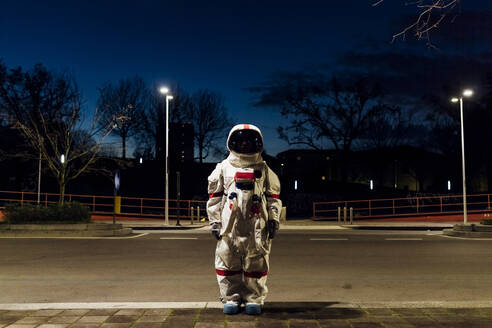 Junge Astronautin im Raumanzug auf einem nächtlichen Fußweg - MEUF02513