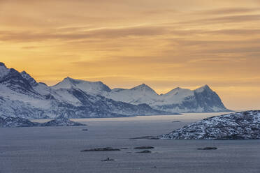 Norwegen, Tromso, Kvaloya, Dramatischer Himmel über dem schneebedeckten Berg Senja Island von der Insel Kvaloya aus gesehen bei Sonnenuntergang - RUEF03266