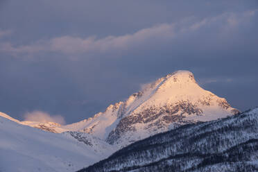 Norwegen, Tromso, Schneebedeckter Berggipfel im Licht des Sonnenaufgangs - RUEF03271