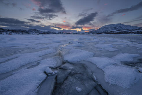 Norwegen, Tromso, Gefrorener See auf der Insel Senja bei Sonnenaufgang - RUEF03276
