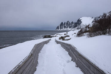 Norwegen, Tromso, Ersfjord, Verschneite Straße entlang der Meeresküste der Insel Senja - RUEF03283