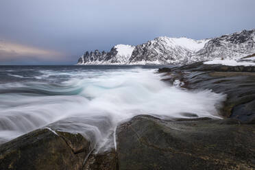 Norwegen, Tromso, Ersfjord, Meereswellen an der felsigen Küste der Insel Senja im Winter - RUEF03286