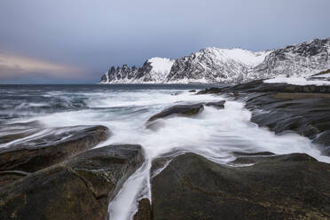 Norwegen, Tromso, Ersfjord, Meereswellen an der felsigen Küste der Insel Senja im Winter - RUEF03287