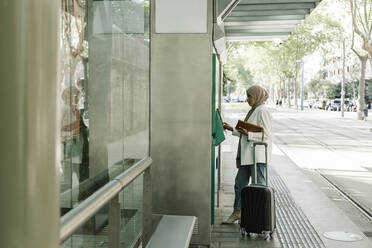 Frau mit Koffer an einem Fahrkartenautomaten im Bahnhof - XLGF01568