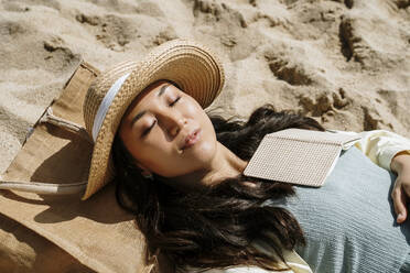 Frau mit geschlossenen Augen im Sand liegend an einem sonnigen Tag - AFVF08666