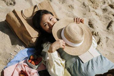 Frau mit Hut liegt am Strand in der Sonne - AFVF08670
