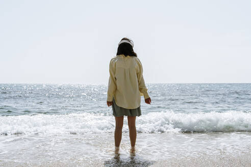 Frau mit Kopfhörern am Strand an einem sonnigen Tag - AFVF08676