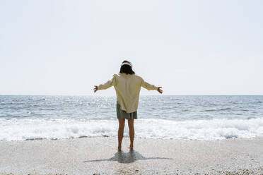 Frau mit ausgestreckten Armen am Strand an einem sonnigen Tag - AFVF08677